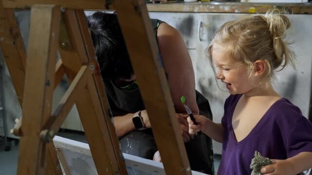 Child painting with an grandmother in a cozy art studio. Candid indoor moment of creativity and learning. Artistic lifestyle scene with real people and natural light.