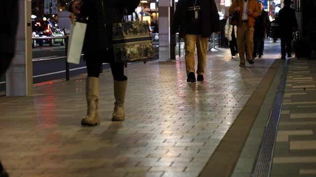 People walking in front of wooden vertical slats wall with warm lighting, urban lifestyle scene captured in real time. Ideal for business, lifestyle and modern city background footage.