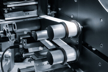 Obraz premium industrial machine with precise rollers. Metal parts move in synchronized motion. Mechanical precision dominates the scene. Ideal for manufacturing or automation contexts
