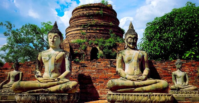 Row of ancient Buddha statues wearing saffron robes at Wat Yai Chai Mongkhon temple complex with main chedi in Ayutthaya, Thailand