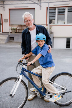 Father teaching son to ride a bicycle outdoors with helmet and trust