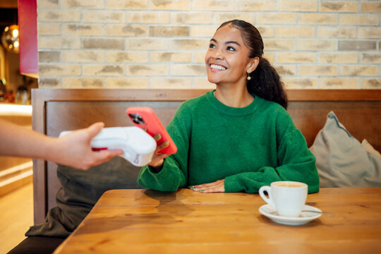 Customer paying with smartphone at cafe using contactless terminal