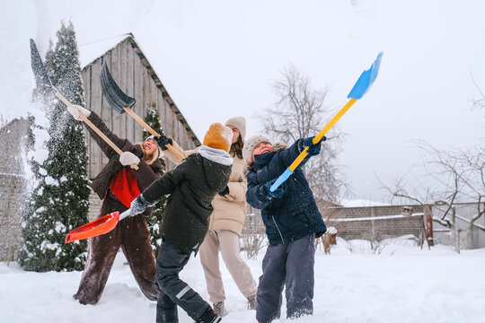 Family enjoying snow shoveling together in a rural winter backyard