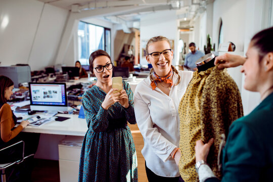 Fashion designers reviewing blouse on mannequin in modern office