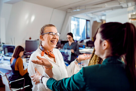 Smiling colleagues welcoming teammate in modern office