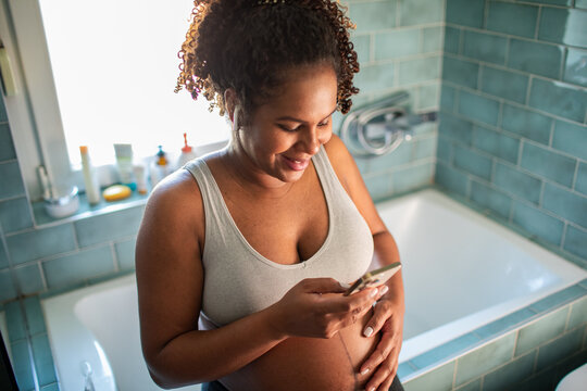 Pregnant woman using smartphone in bathroom