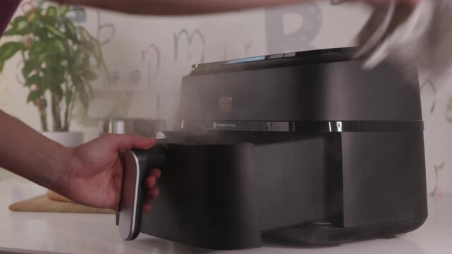 Man waving towel to clear smoke from burning food in air fryer