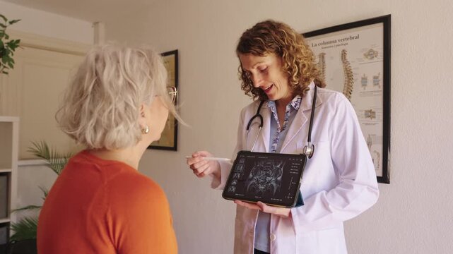 Female doctor showing pelvic x ray on tablet to elderly patient