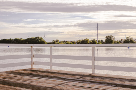 Wooden lake jetty with white railings and wind turbines sunset in Żnin, Kuyavian-Pomeranian Voivodeship, Poland