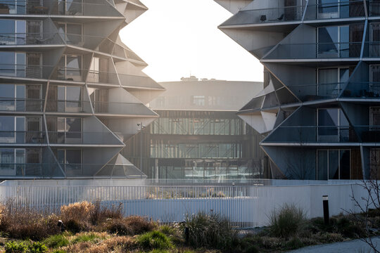 Backlit modern urban architecture showing a complex of buildings where sunlight shapes facade geometry against a landscape setting in a dramatic contemporary city view
