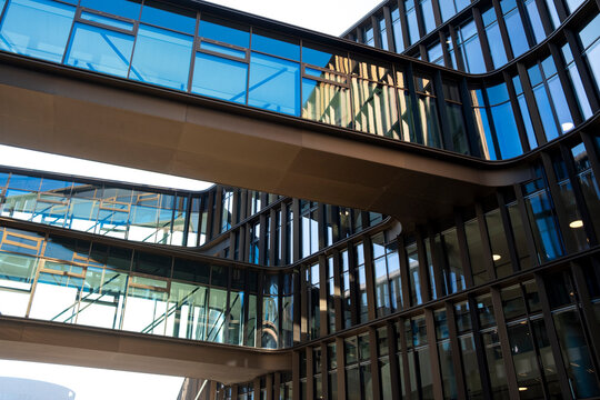 Glass architecture with a skybridge walkway where modern building windows reflect across an urban structure connecting spaces with clean contemporary geometry and lines