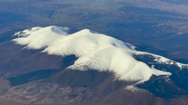 Spinning aerial view of El Moncayo Mountain in Aragon (Spain), covered by snow, captured from an airplane cockpit at 8000m high.