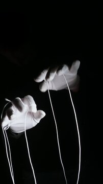 Vertical 4K shot of white-gloved hands controlling strings like a puppet master. Symbolizes political power, manipulation, authority, and control.