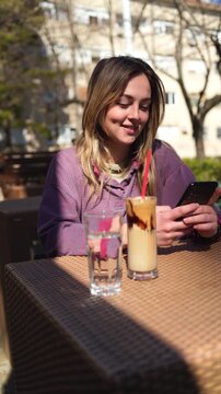 Young woman in a cafe outdoors using a mobile phone