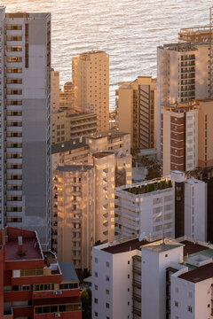 Sunset light over sea coast frames the urban skyline of highrise towers in Benidorm Spain with warm sunlight glow and dense cityscape