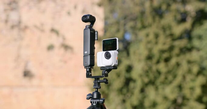 Tripod-mounted multi-camera setup with action cameras outdoors. Filmmaking rig for vlogging and multi-angle recording