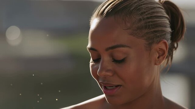 Pressing spray bottle, bare-shouldered woman spraying facial mist at sunlit scene hydrating skin