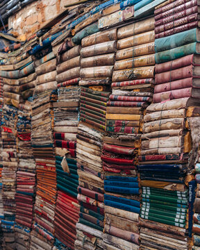 View of a towering wall of stacked vintage books, their aged pages and vibrant spines creating a textured tapestry of literary history, Venice, Veneto, Italy.