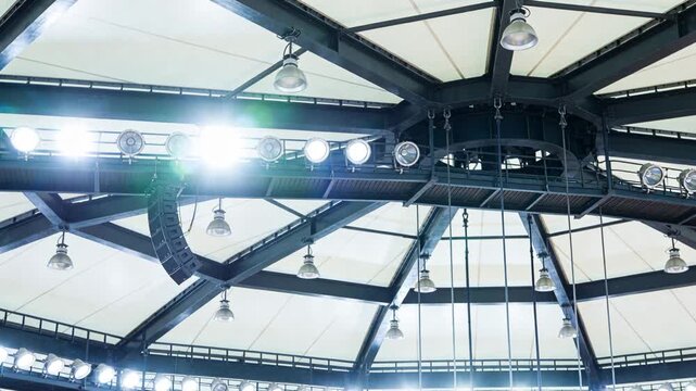 Showing central dome hub lighting rig brightening after lighting cue in arena, with ring fixtures