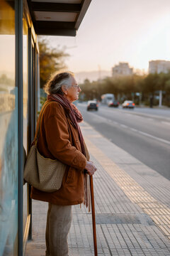 A woman in a brown coat and scarf stands on a sidewalk next to a bus stop
