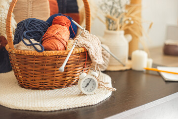 Obraz premium Balls of yarn and knitting needles in a wicker basket. A knitter's workspace.