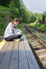 Fototapeta premium Girl waiting for the train on the small rails station, Train schedule, buy tickets online,