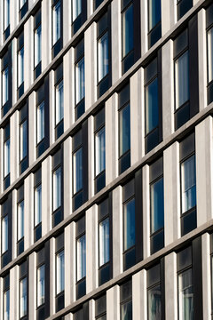 Modern office building architecture facade with repeating windows grid showing symmetry and clean lines forming an abstract pattern background