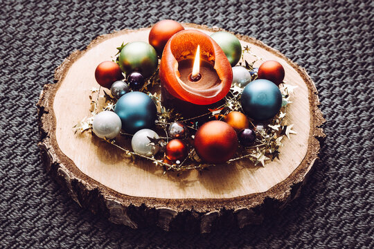 Kerze mit bunten Weihnachtskugeln auf einer Holzplatte, Perspektive, moderne Weihnachtsdeko auf Holzscheibe