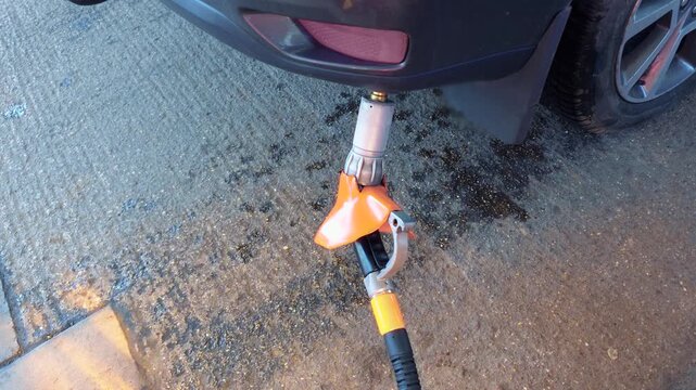 LPG car refueling with gas nozzle connected to vehicle tank for alternative fuel savings. Autogas usage reducing fuel expenses during global energy crisis caused by war and rising petrol prices