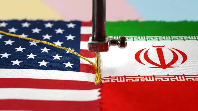 macro shot of sewing needle with golden thread joining edges of two canvases in form of usa and iran flags creating metaphor for restoring diplomatic ties and lasting peace