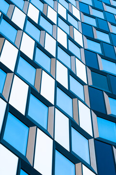 Blue glass architecture facade with modern building windows pattern forming abstract geometry and clean urban design texture in daylight exterior