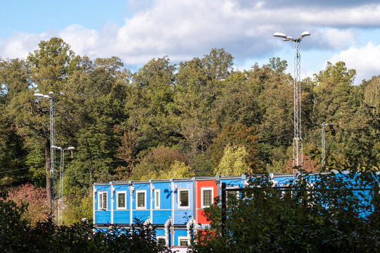 Colorful modular building made of containers at a construction site in daylight beside forest showing architecture contrast and modern development