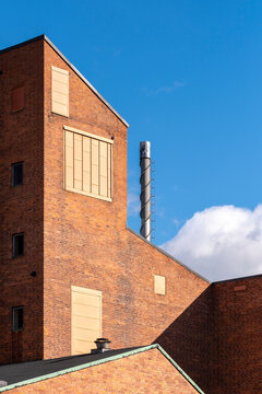 Industrial architecture building in brick with chimney facade corner under sky in sunlight with minimalism and strong geometry for modern background