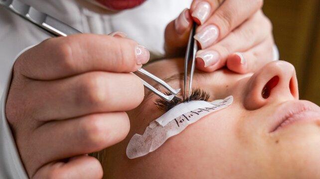 Professional applying eyelash extensions with tweezers for a glamorous look
