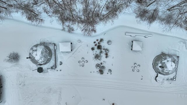 Dome or igloo style glamping tents covered in snow, birds eye view