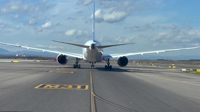 External rear view of a massive twin-engine long-range jet taxiing slowly to the runway ready for departure. Scene taken from an aiplane cockpit taxiing behind.