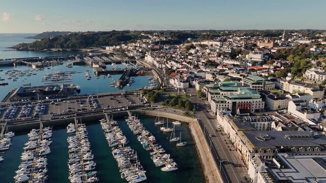 St Peter Port Guernsey,QEII marina drone flight over marina and Glategny Esplanade with views over main harbour,St Peter Port townscape and to the wooded cliffs of St Martins in late afternoon.