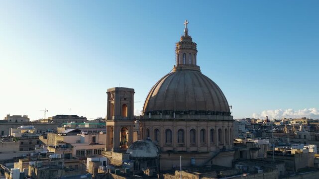 Iconic Dome Of Basilica of Our Lady of Mount Carmel Against Clear Blue Sky At Sunrise in Valletta, Malta. orbiting drone shot