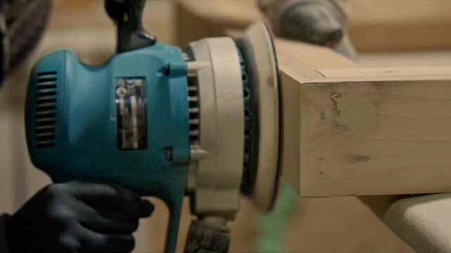 Carpenter using orbital sander on wood furniture