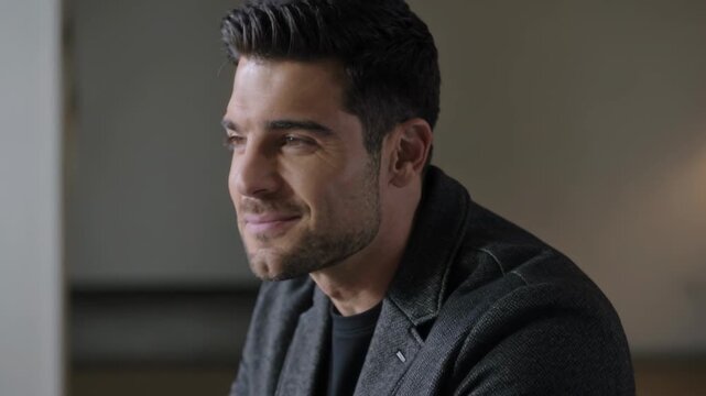 Smiling professional man reacting to off-frame prompt at studio, wearing dark blazer, copy space