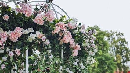 Obraz premium Pink and white roses and hydrangeas decorating a white metallic gazebo