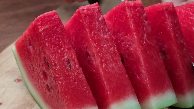Fresh watermelon slices arranged on a wooden plate.