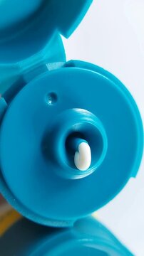 Extreme close up of white cream dispensing from turquoise packaging, smooth skincare texture.