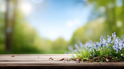 A wooden table in a spring scene with bluebells in grass against a blurred green background offers space for product showcase
