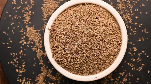 Top View of Carom Seeds (Ajwain) in White Bowl on Black Background &ndash; Rotating Footage