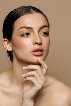 Beautiful young woman with clean fresh skin on beige background,