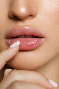 Young woman with beautiful full lips on beige background