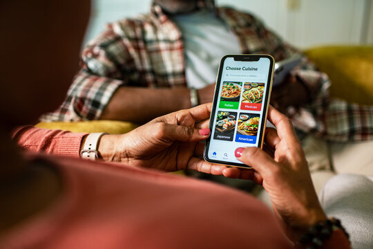 Woman choosing cuisine on food delivery app at home