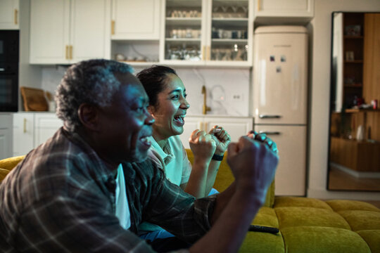 Excited man and woman cheering while watching sports at home