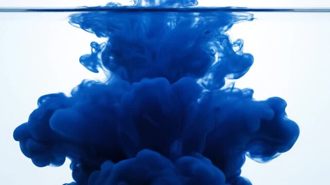 A single droplet of vibrant blue ink dissolving and blooming into a cloud within pure water
